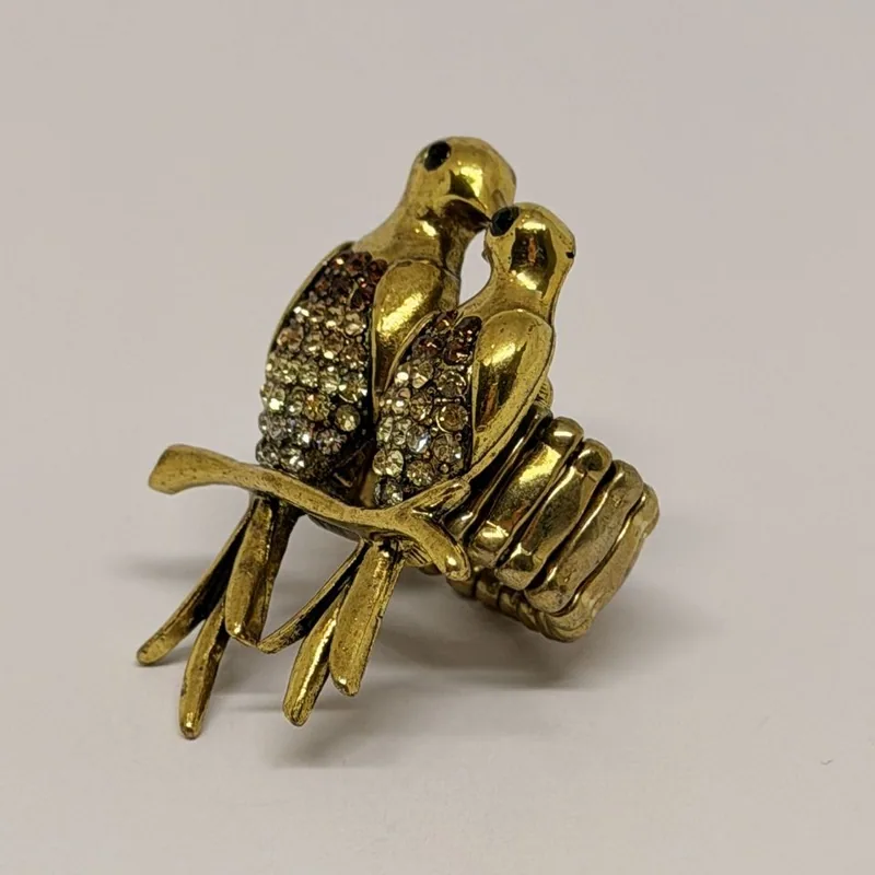 Anel dourado com casal de pássaros cravejados sobre galho e aro articulado — ref. ANQ0192A