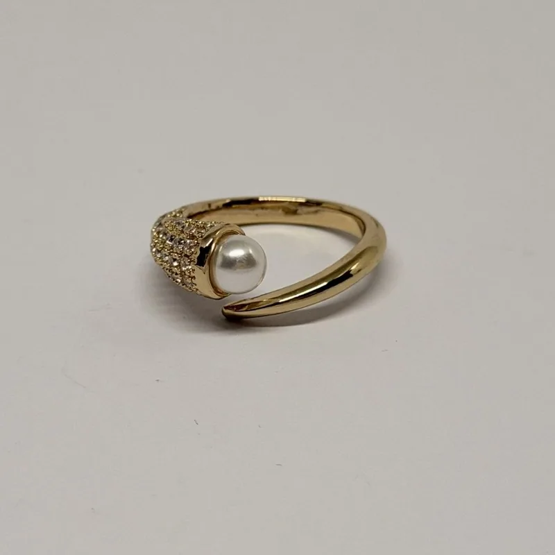 Anel dourado com aros cruzados, um cravejado, e pérola ao centro — ref. ANQ0034A