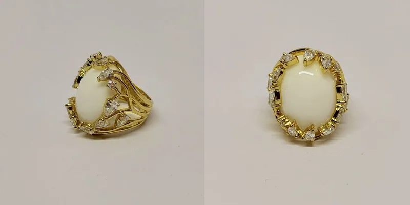 Anel dourado com cabochão branco oval em garras trabalhadas — ref. ANL0031A