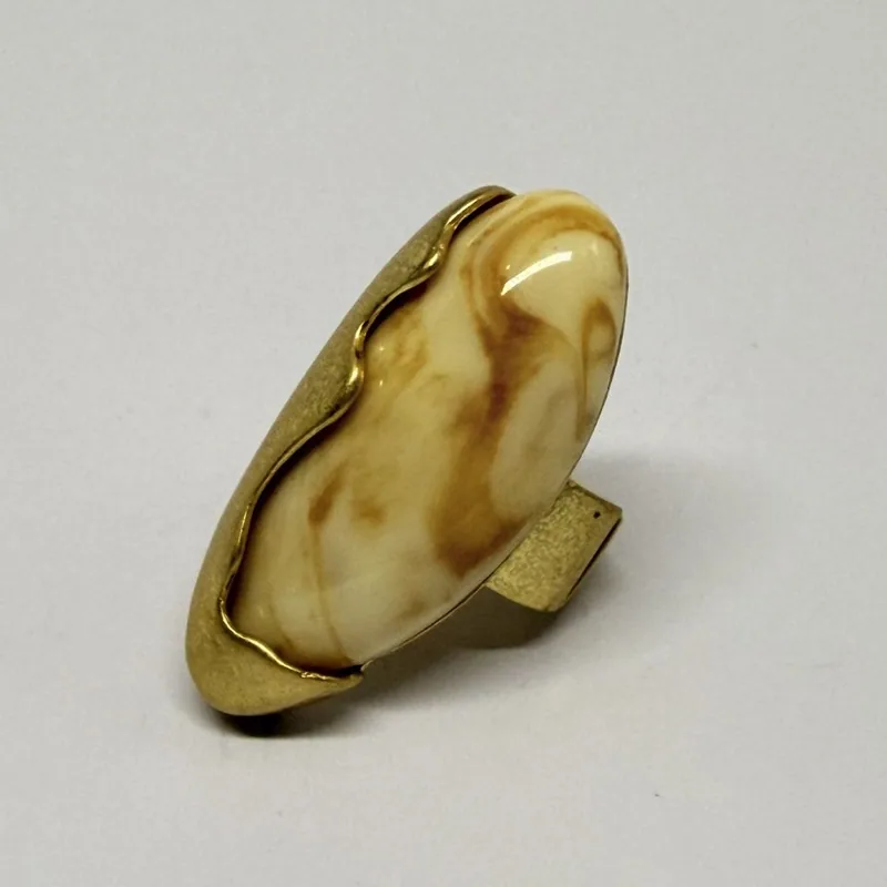 Anel dourado com pedra clara marmorizada alongada em moldura ondulada — ref. ANQ0079A