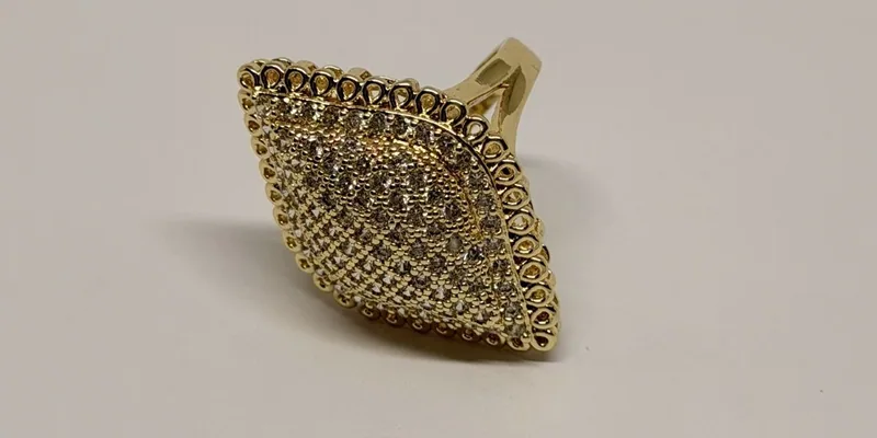 Anel dourado com pedra rosa e halo de cristais