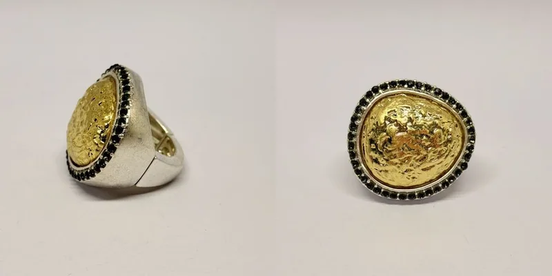 Anel prateado com medalhão oval dourado gravado e contorno de cristais escuros — ref. ANL0142A
