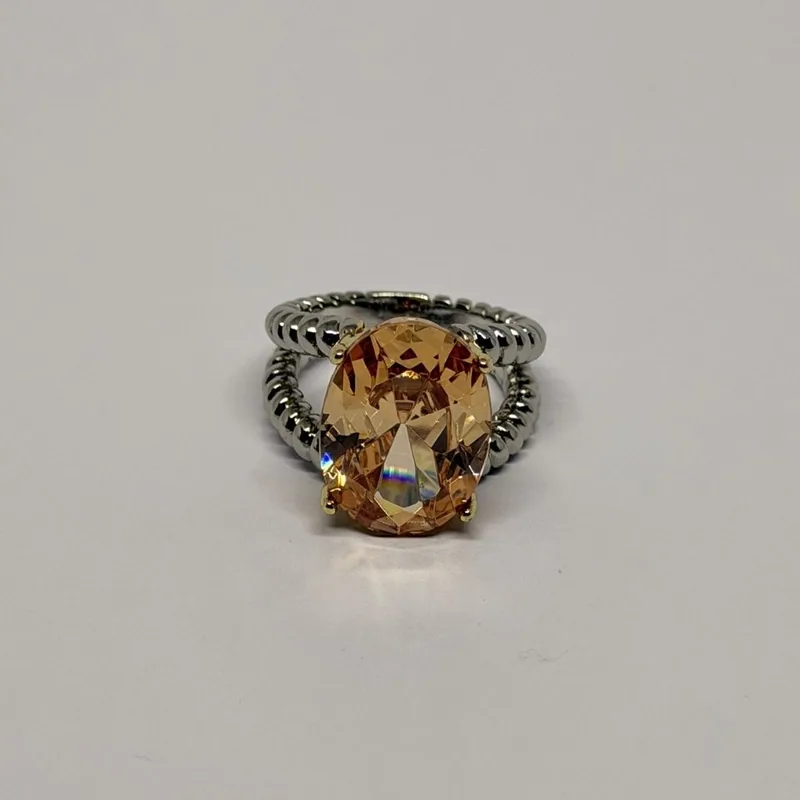Anel prateado com pedra champanhe oval em garras douradas e aro duplo em esferas — ref. ANQ0143A