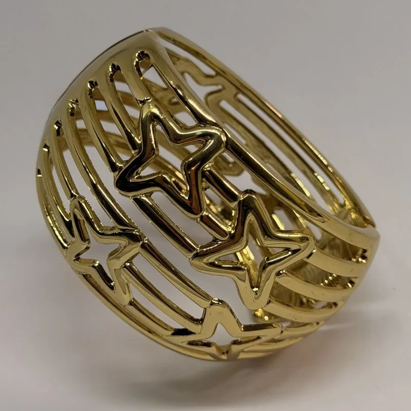 Bracelete dourado rígido e largo com estrelas vazadas em relevo — ref. BTE0101A